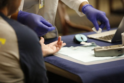 Nurse taking finger stick blood sample from staffmember